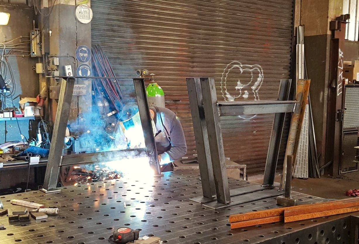 Schweißen eines Stahl-Tischgestells in der eigenen Metallbearbeitung – Holz- und Stahl-Lösungen aus Essen